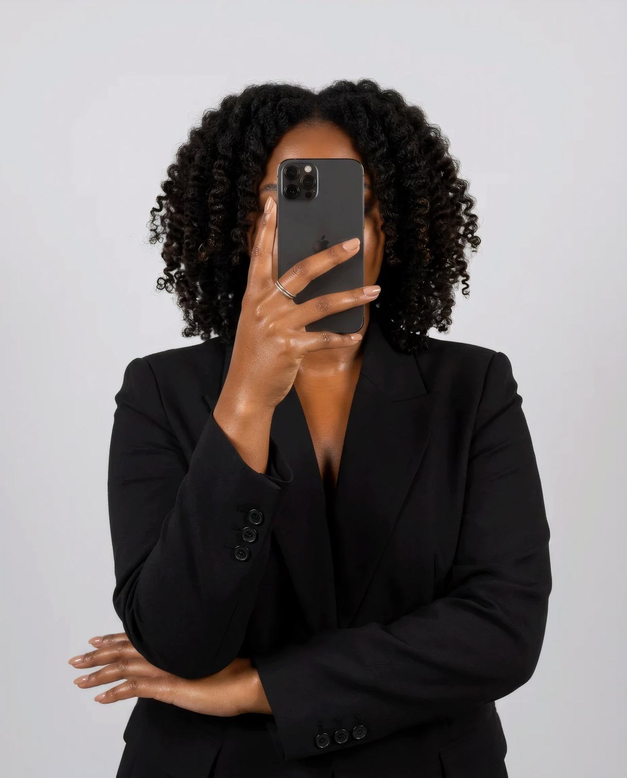 A woman in a black blazer holding a phone in front of her face