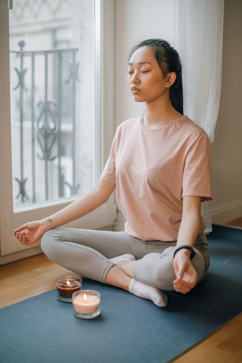 A woman meditating by candlelight